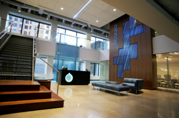 Lobby of Acquia with stairs to left and wall of screens to right