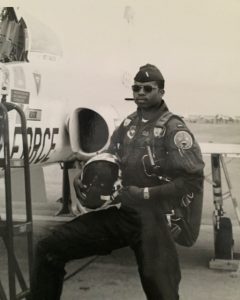 Chevy Cleaves in flight gear standing next to an airplane