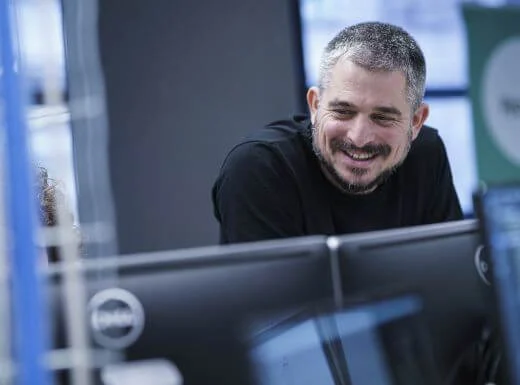 Smiling man leaning forward as if talking to someone over a desk